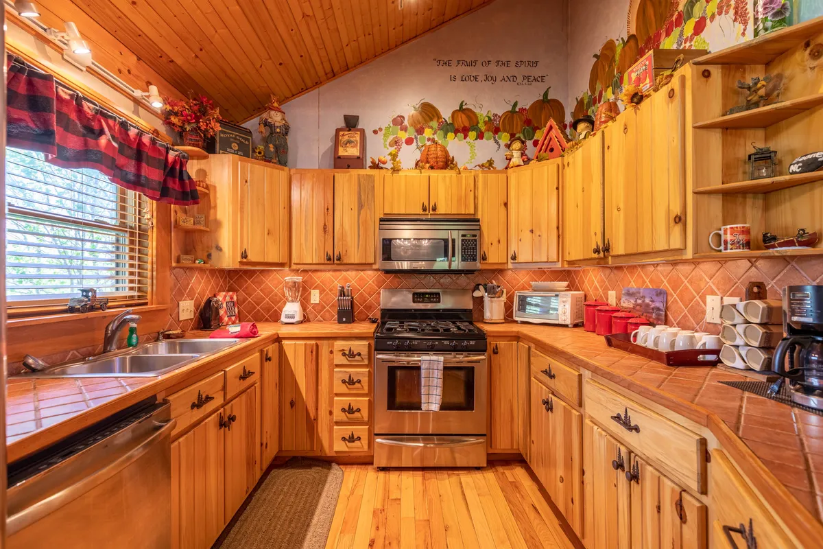 A fully equipped kitchen with wooden cabinetry and stainless steel appliances, centered around a functional kitchen island. The warm decor and decorative wall mural add a touch of rustic charm, making it inviting for cooking and socializing.