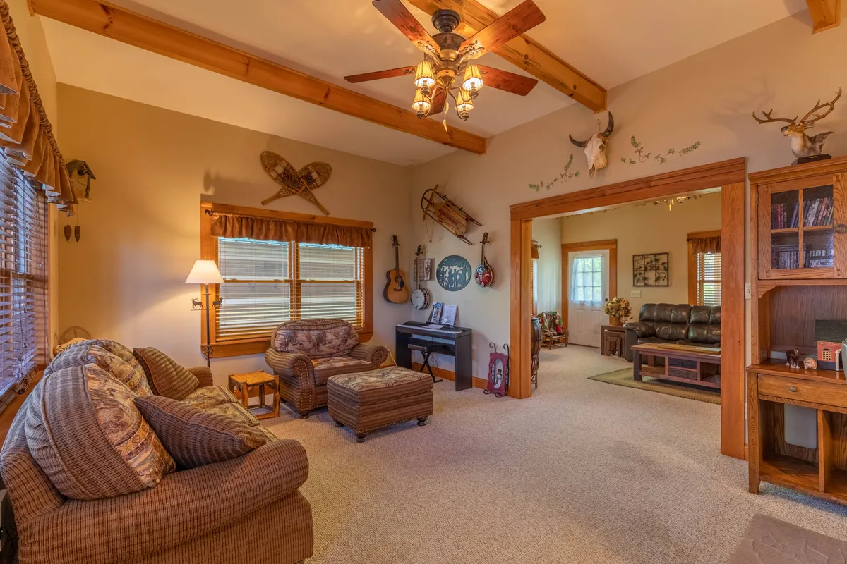 A comfortable living area with a sofa and armchair, featuring a piano and a bookshelf along one wall. The decorative wall art and soft lighting evoke a homely atmosphere, and the piano suggests opportunities for music-making.